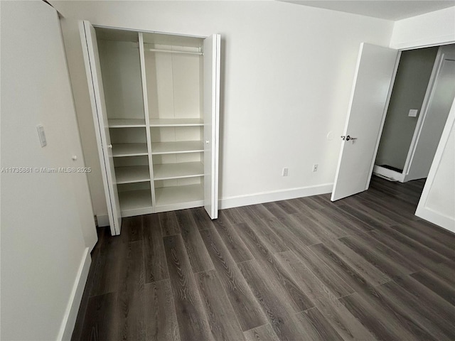 unfurnished bedroom with dark wood-type flooring and a closet