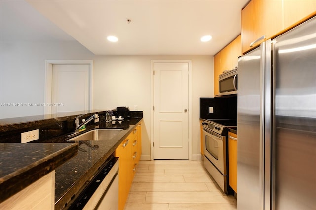 kitchen featuring stainless steel appliances, sink, and dark stone countertops