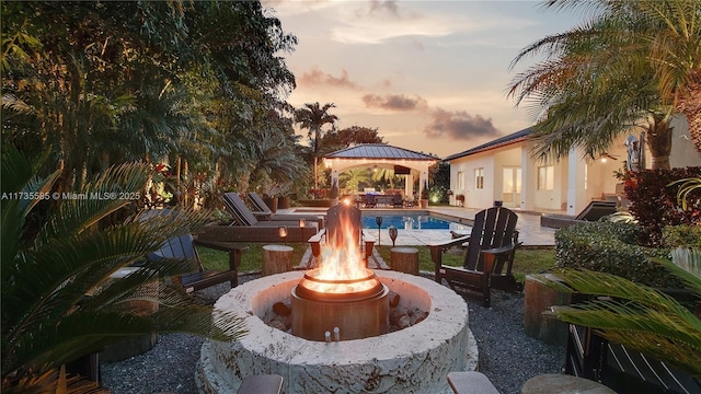 patio terrace at dusk featuring a gazebo and a fire pit