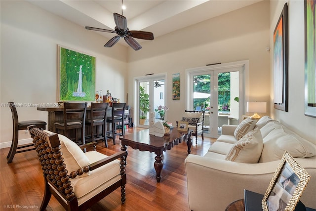 living room with dark wood-type flooring, bar area, and ceiling fan