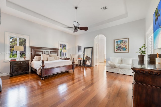 bedroom featuring a raised ceiling, hardwood / wood-style floors, and ceiling fan