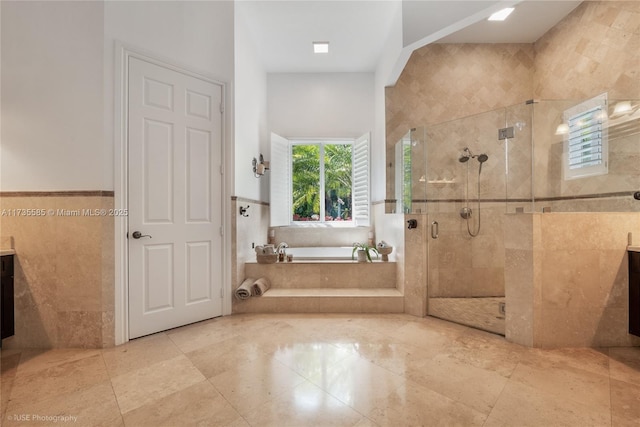 bathroom with vanity, shower with separate bathtub, and tile walls