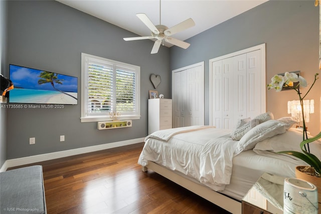 bedroom featuring lofted ceiling, dark wood-type flooring, two closets, and ceiling fan