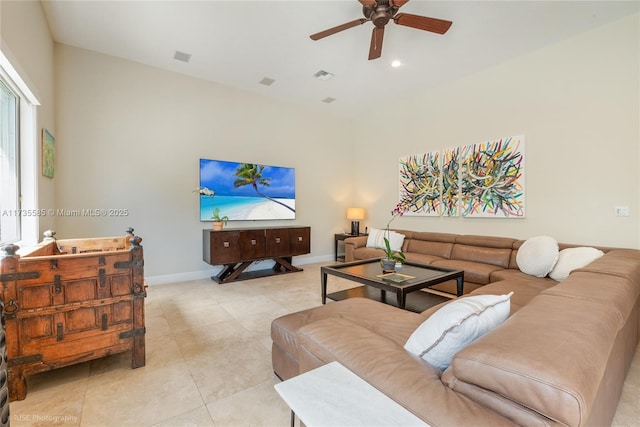 living room with ceiling fan, a towering ceiling, and light tile patterned floors