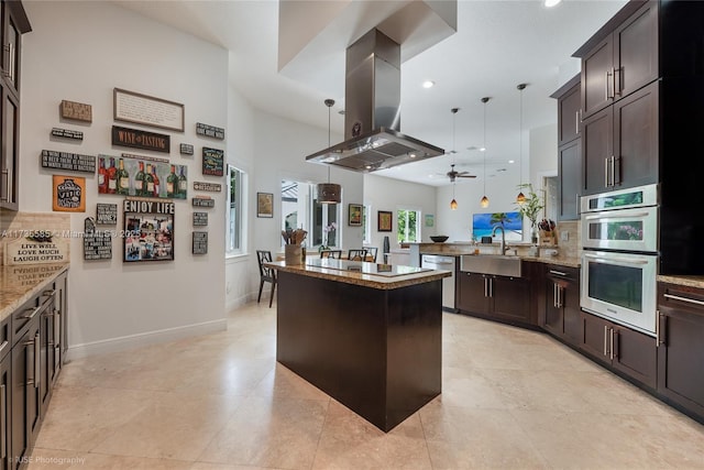 kitchen featuring light stone counters, decorative light fixtures, a center island, appliances with stainless steel finishes, and island exhaust hood