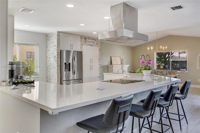 kitchen with stainless steel refrigerator with ice dispenser, a kitchen bar, sink, white cabinetry, and island range hood