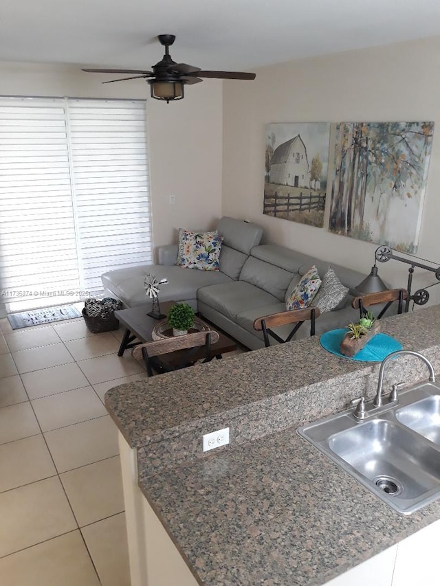 unfurnished living room featuring tile patterned flooring, sink, and ceiling fan