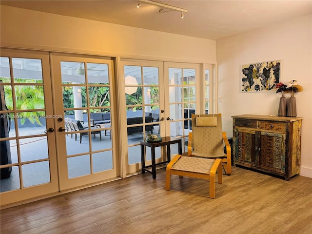 sitting room with a healthy amount of sunlight, hardwood / wood-style floors, track lighting, and french doors