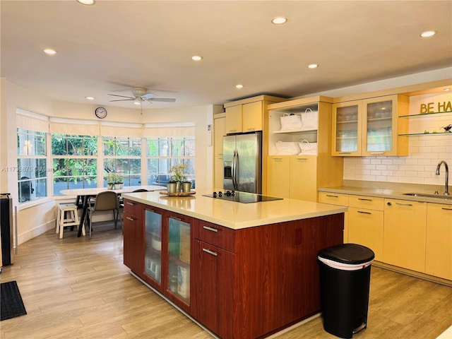 kitchen with sink, a center island, light hardwood / wood-style floors, stainless steel fridge with ice dispenser, and black electric cooktop