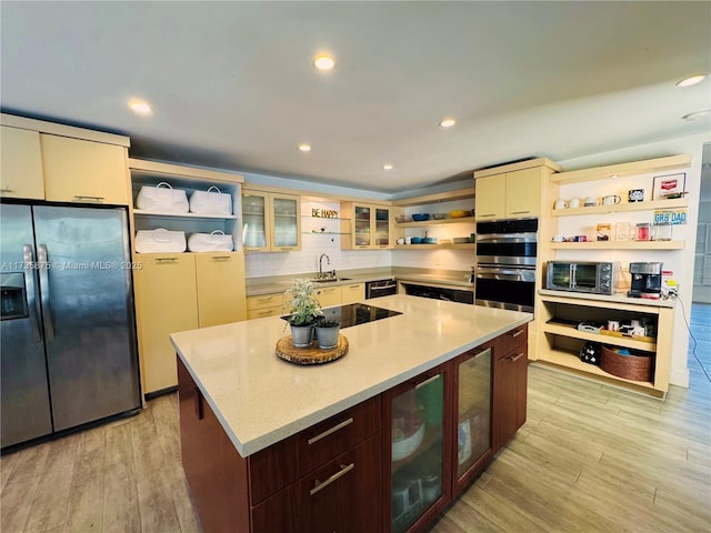 kitchen featuring sink, light hardwood / wood-style flooring, a kitchen island, cream cabinets, and black appliances