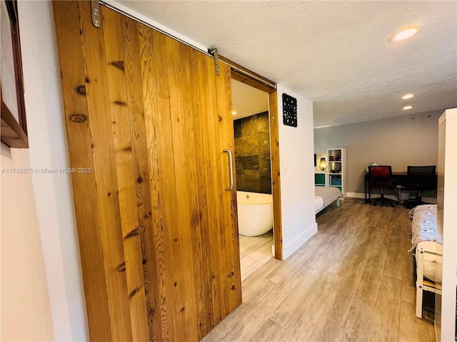 hallway featuring light hardwood / wood-style floors and a textured ceiling