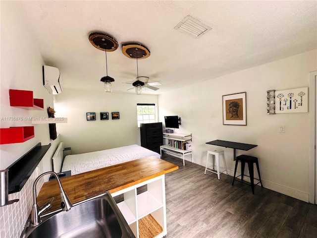 interior space with sink, a wall mounted air conditioner, a textured ceiling, dark hardwood / wood-style floors, and ceiling fan