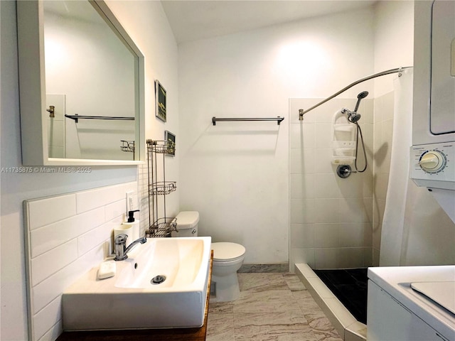 bathroom featuring a tile shower, sink, backsplash, and toilet