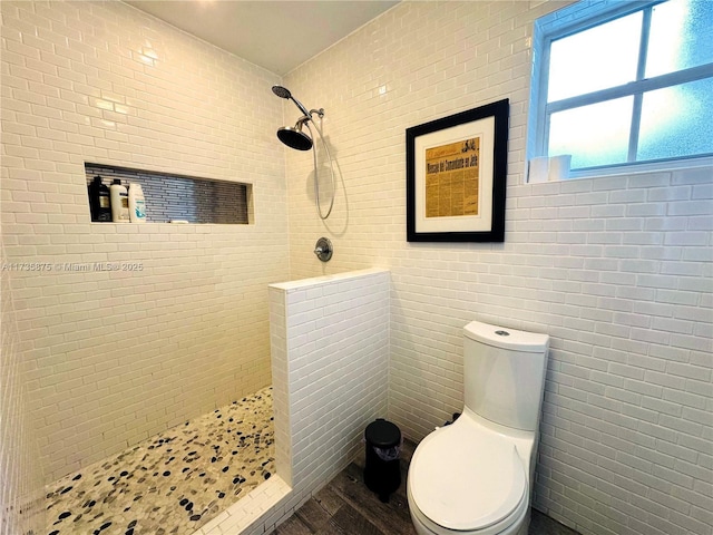 bathroom featuring hardwood / wood-style flooring, toilet, and tiled shower