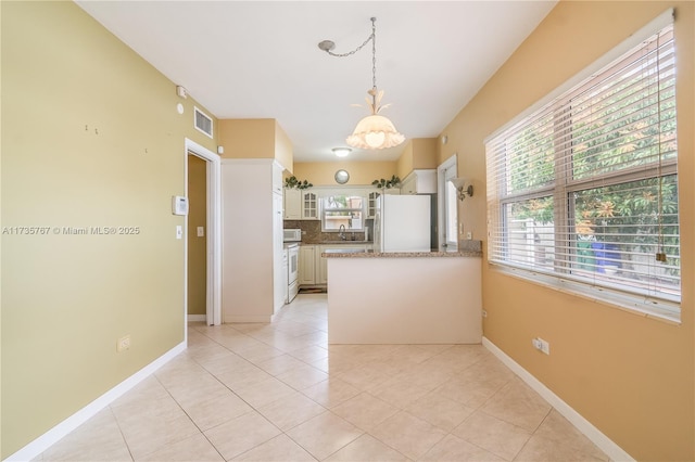 kitchen featuring white cabinetry, decorative backsplash, white refrigerator, light tile patterned floors, and kitchen peninsula