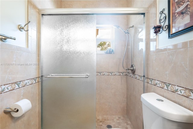 bathroom featuring a shower with door, tile walls, and toilet