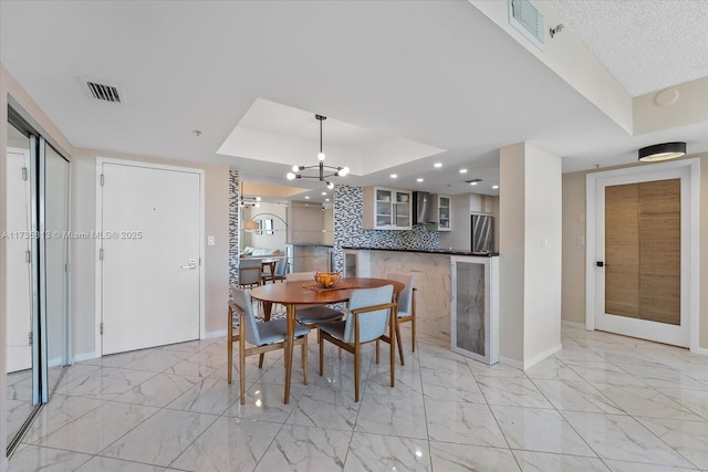 dining area with a raised ceiling and a notable chandelier