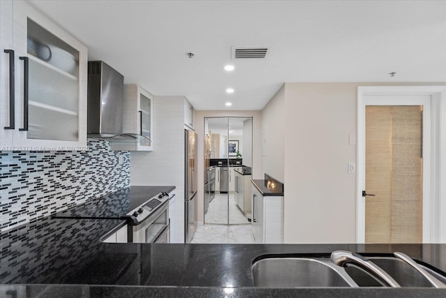 kitchen with appliances with stainless steel finishes, wall chimney exhaust hood, sink, and backsplash