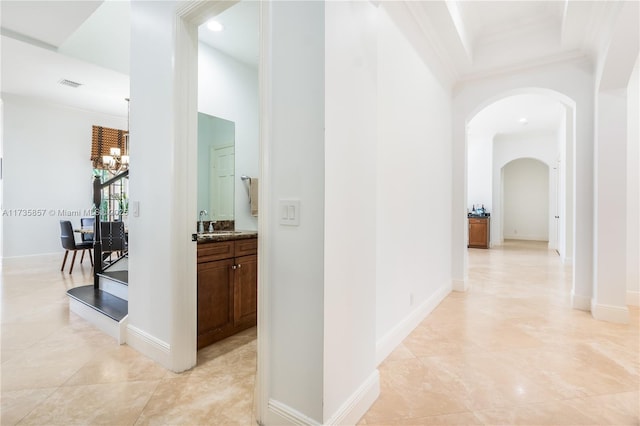 corridor featuring a notable chandelier, crown molding, sink, and a high ceiling