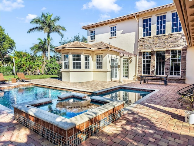 rear view of property featuring a swimming pool with hot tub and a patio area