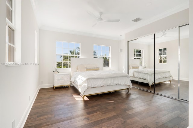 bedroom featuring dark wood-type flooring, ceiling fan, ornamental molding, and a closet