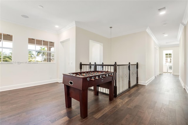 recreation room with plenty of natural light, ornamental molding, and dark hardwood / wood-style floors