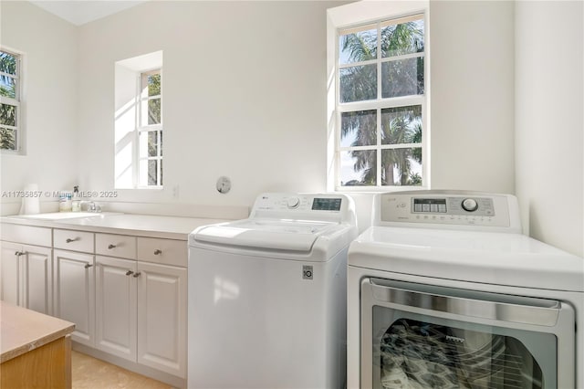 clothes washing area featuring sink, cabinets, and washing machine and clothes dryer