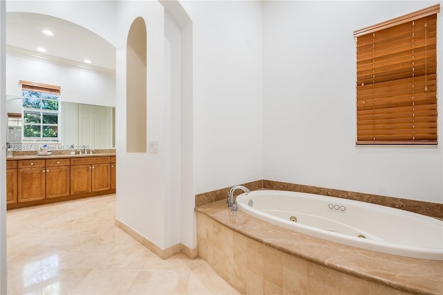 bathroom with tile patterned flooring, ornamental molding, tiled bath, and vanity