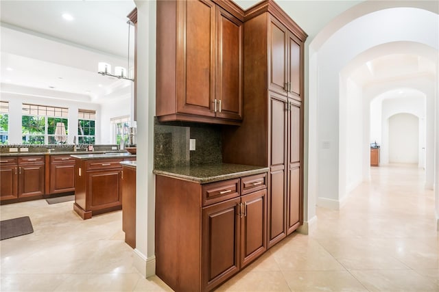 kitchen featuring light tile patterned floors, dark stone counters, and decorative backsplash