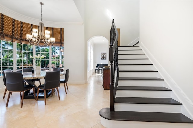 tiled dining space with crown molding, a chandelier, and a towering ceiling