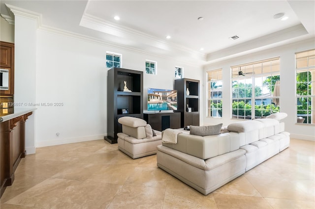 living room featuring built in shelves, ornamental molding, and a raised ceiling