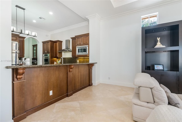 kitchen featuring appliances with stainless steel finishes, decorative light fixtures, dark stone countertops, crown molding, and wall chimney exhaust hood