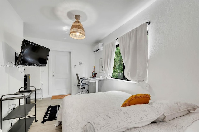 bedroom with an AC wall unit and light hardwood / wood-style floors