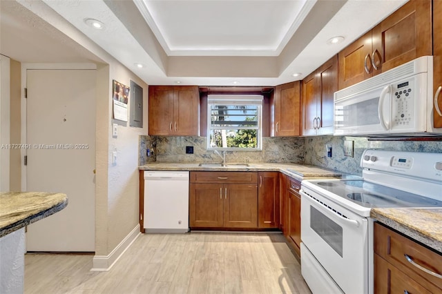 kitchen with white appliances, a tray ceiling, light countertops, and a sink