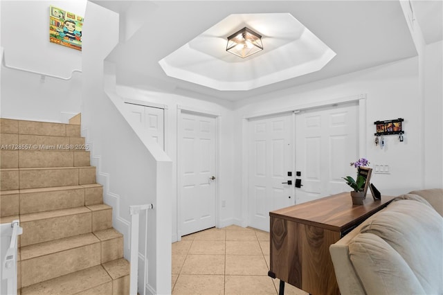 foyer with light tile patterned floors and a raised ceiling