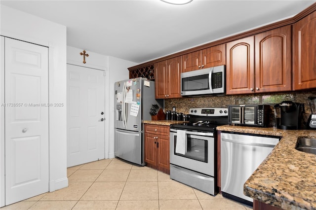 kitchen featuring light tile patterned floors, sink, appliances with stainless steel finishes, light stone counters, and decorative backsplash