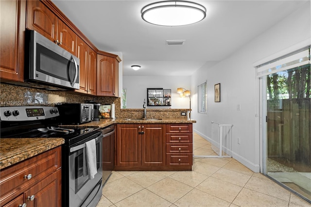 kitchen featuring appliances with stainless steel finishes, kitchen peninsula, sink, and stone countertops