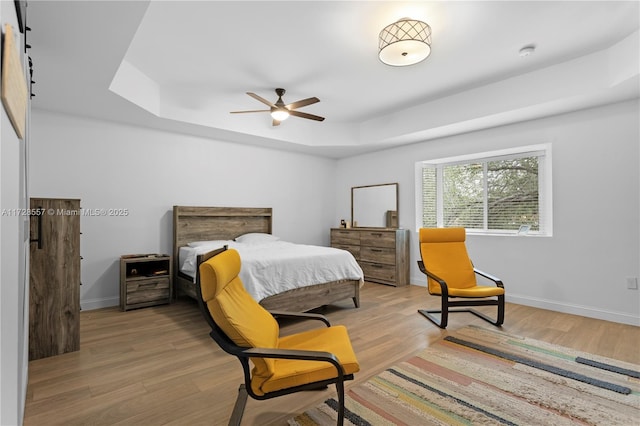 bedroom featuring a tray ceiling and light hardwood / wood-style floors