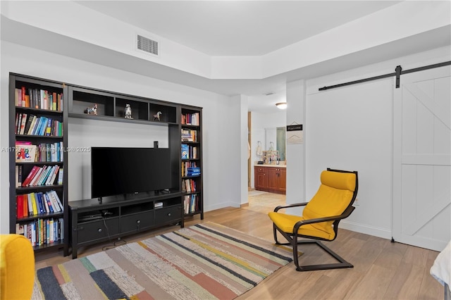 sitting room featuring a barn door and light hardwood / wood-style flooring