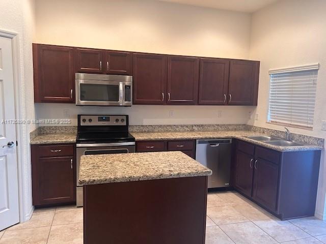 kitchen featuring light tile patterned flooring, stainless steel appliances, a center island, and sink