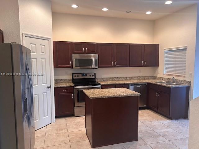 kitchen with stainless steel appliances, light tile patterned flooring, a center island, and sink