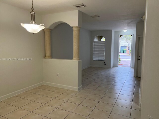 tiled spare room featuring decorative columns