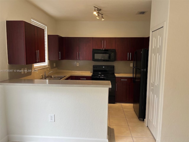 kitchen with light tile patterned flooring, kitchen peninsula, sink, and black appliances