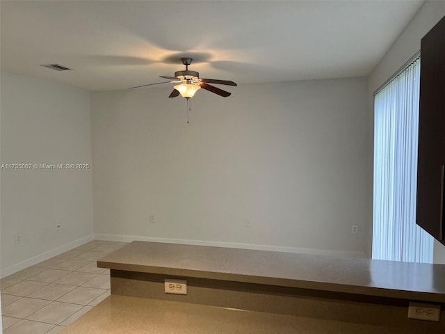 tiled spare room featuring ceiling fan