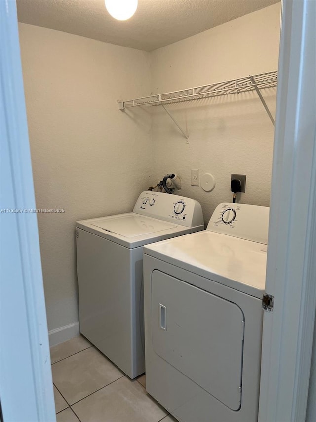 washroom featuring washing machine and dryer, light tile patterned floors, and a textured ceiling