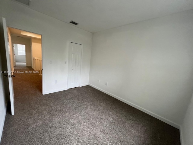 unfurnished bedroom featuring a closet and dark colored carpet