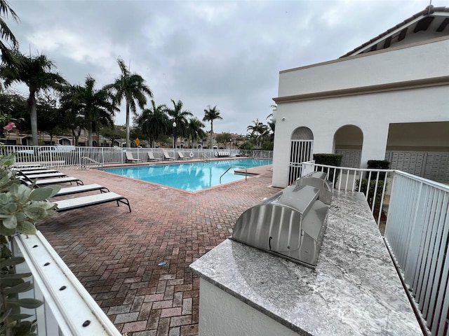 view of swimming pool featuring a patio and an outdoor kitchen