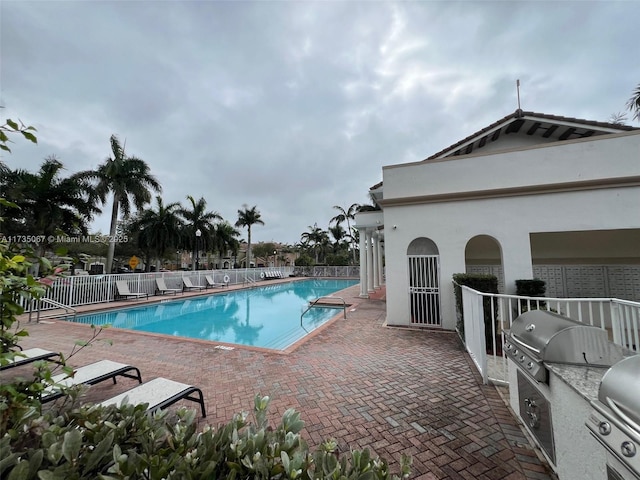 view of pool with an outdoor kitchen, area for grilling, and a patio