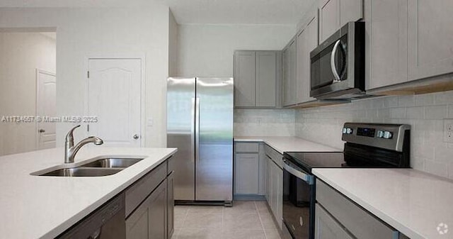 kitchen with gray cabinets, appliances with stainless steel finishes, sink, decorative backsplash, and light tile patterned floors