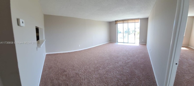 carpeted empty room featuring a textured ceiling and a wall of windows